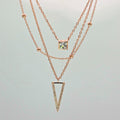 Two rose gold necklaces with gemstone pendants on a light gray background
