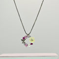 Necklace with floral and berry pendants on a light gray background