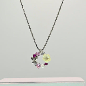 Necklace with floral and berry pendants on a light gray background