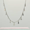 Silver necklace with pendant drops on a light gray background
