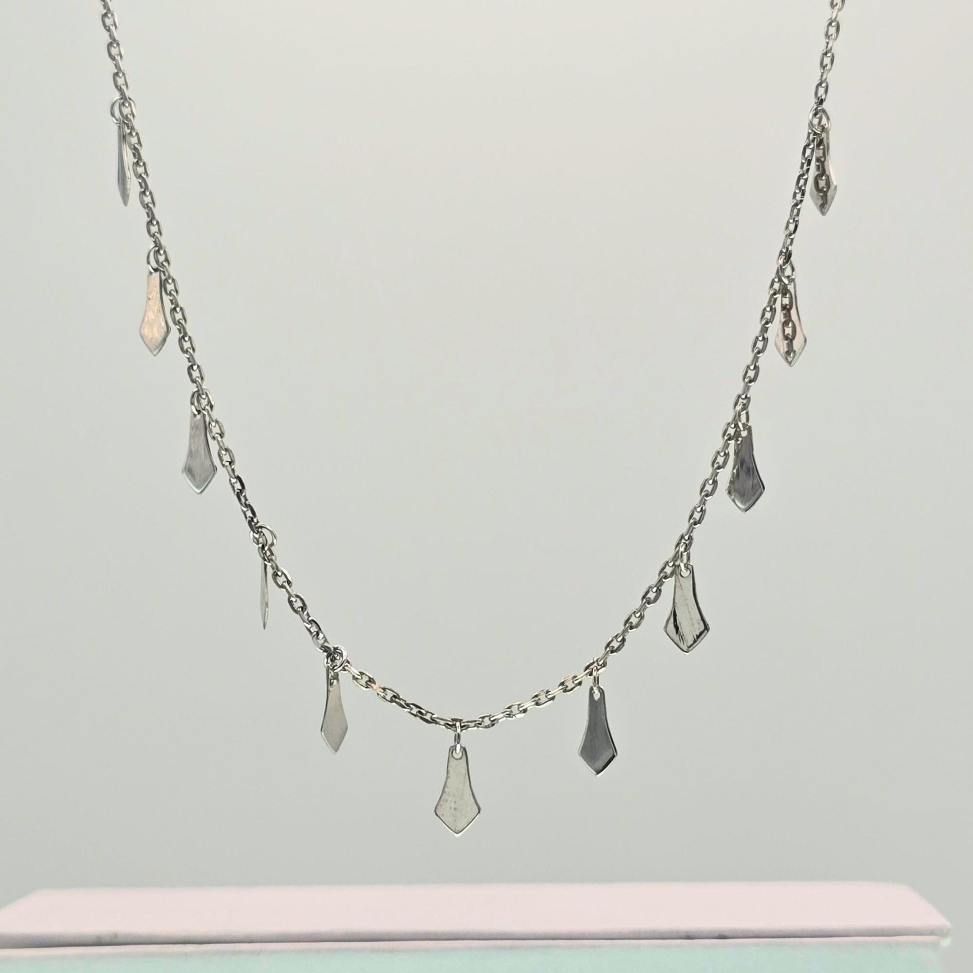 Silver necklace with pendant drops on a light gray background