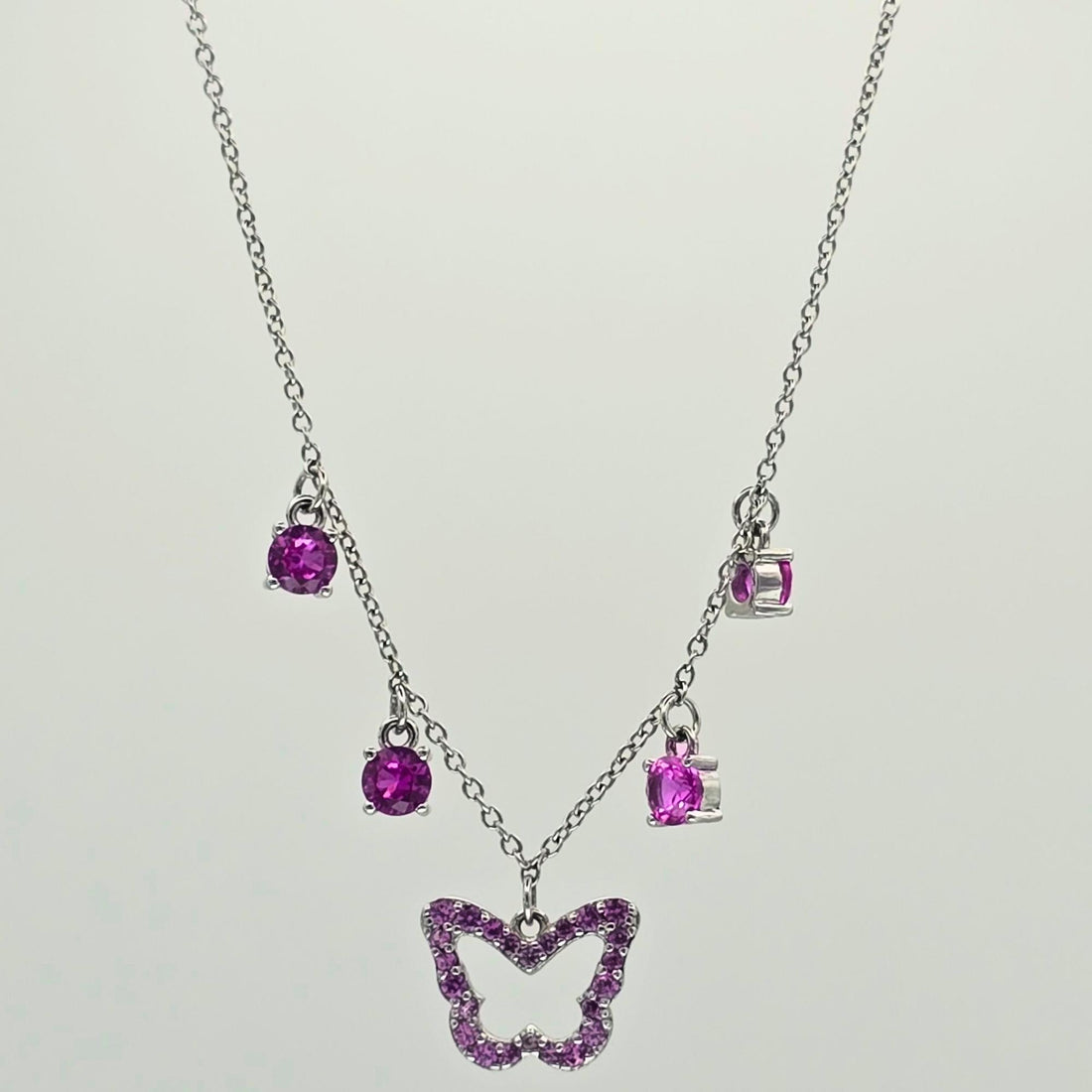 Necklace with a butterfly pendant and purple gemstones on a light gray background
