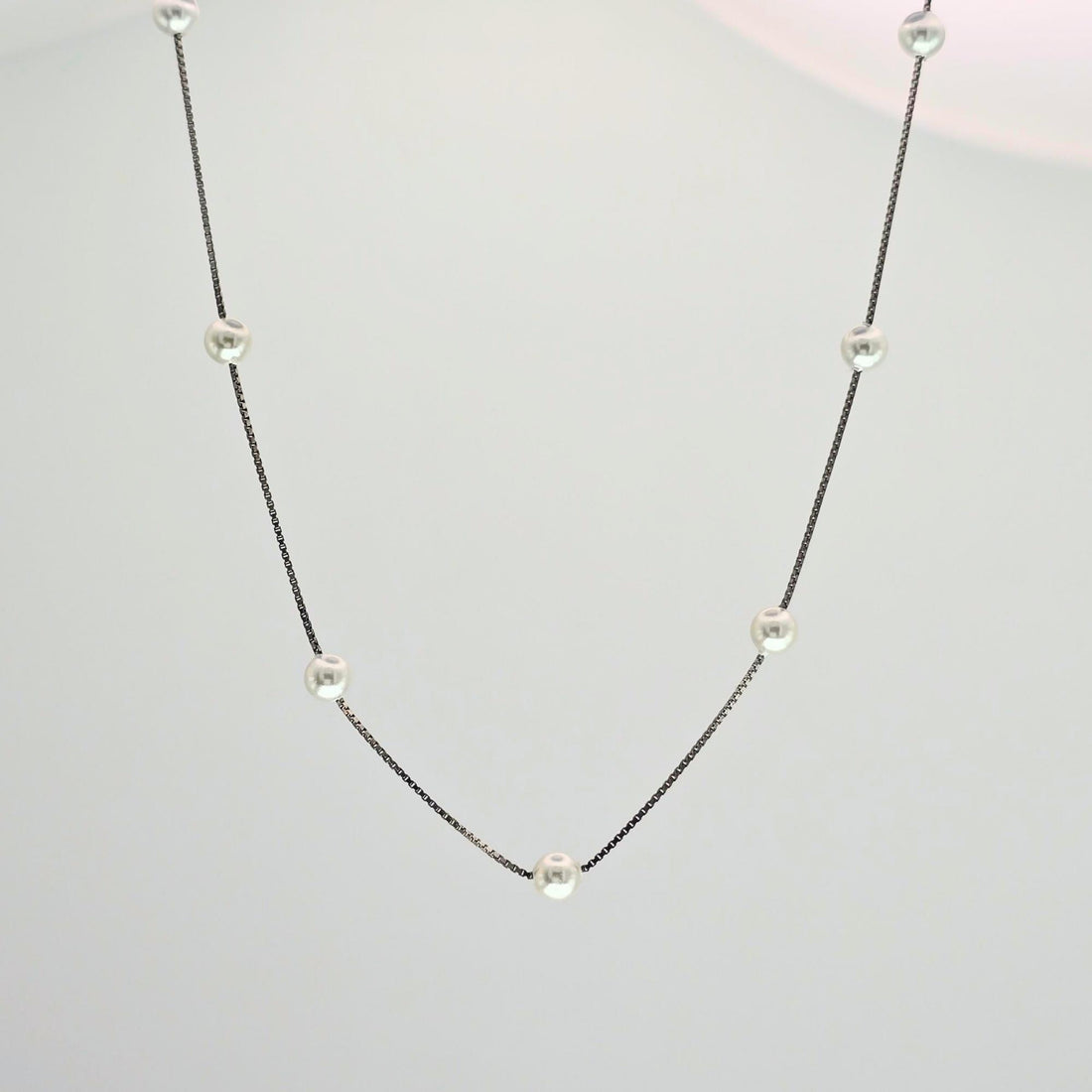 Necklace with small pearls on a light gray background