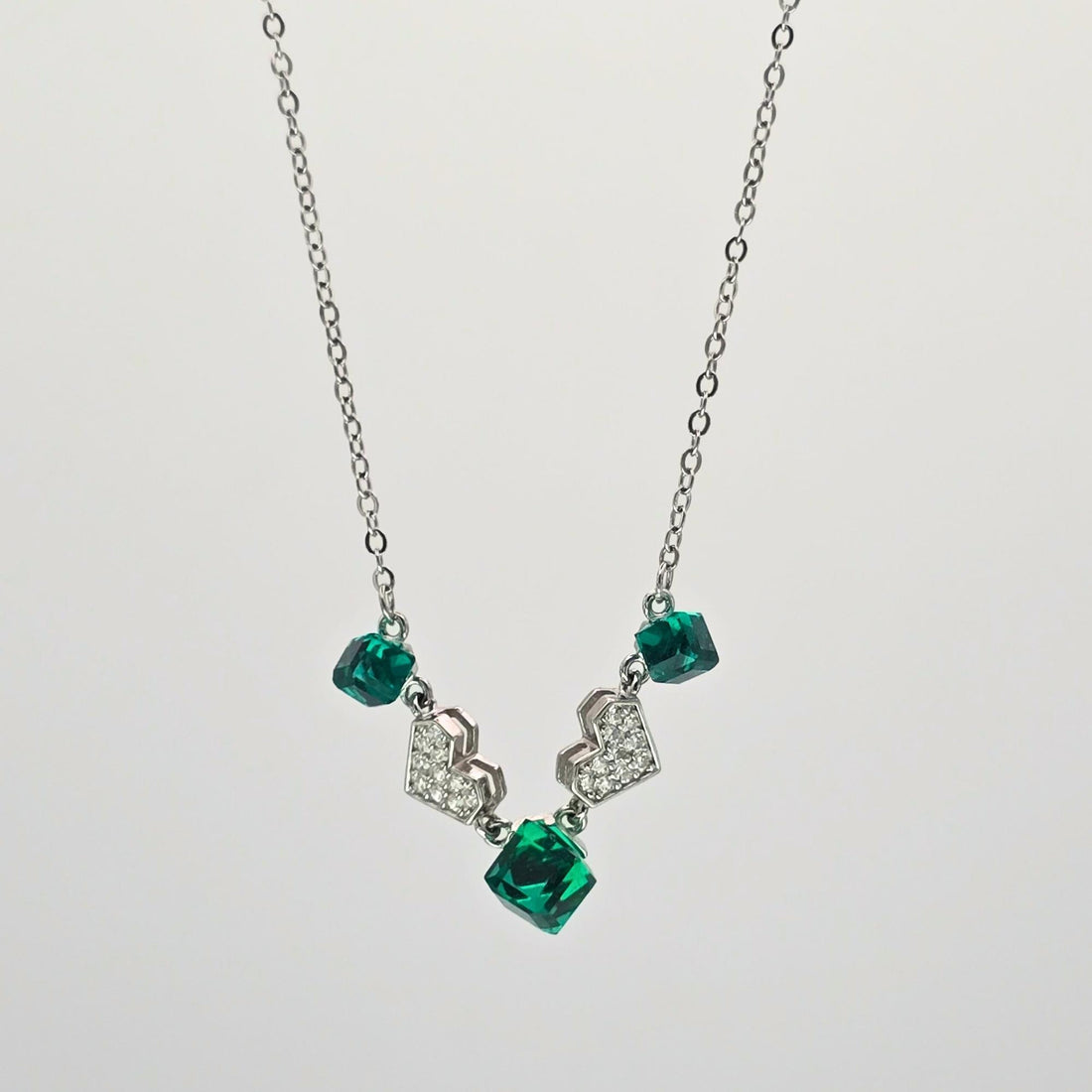 Necklace with green gemstones and silver pendants on a white background