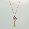 Rose gold heart-shaped key pendant necklace on a light gray background