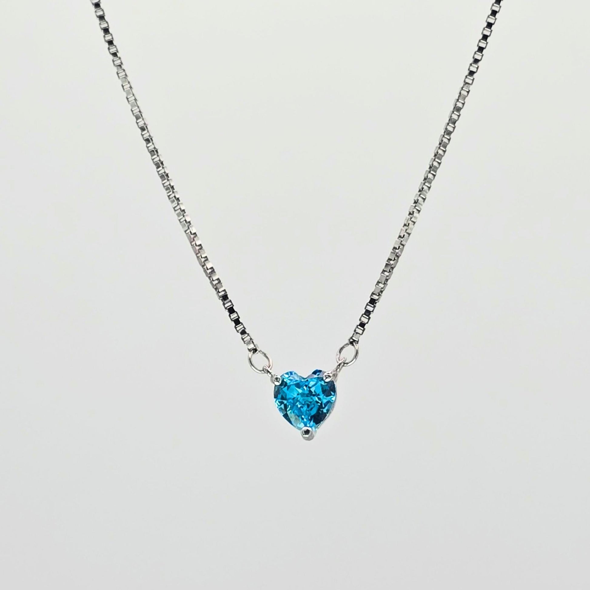 Heart-shaped blue gemstone necklace on a light gray background