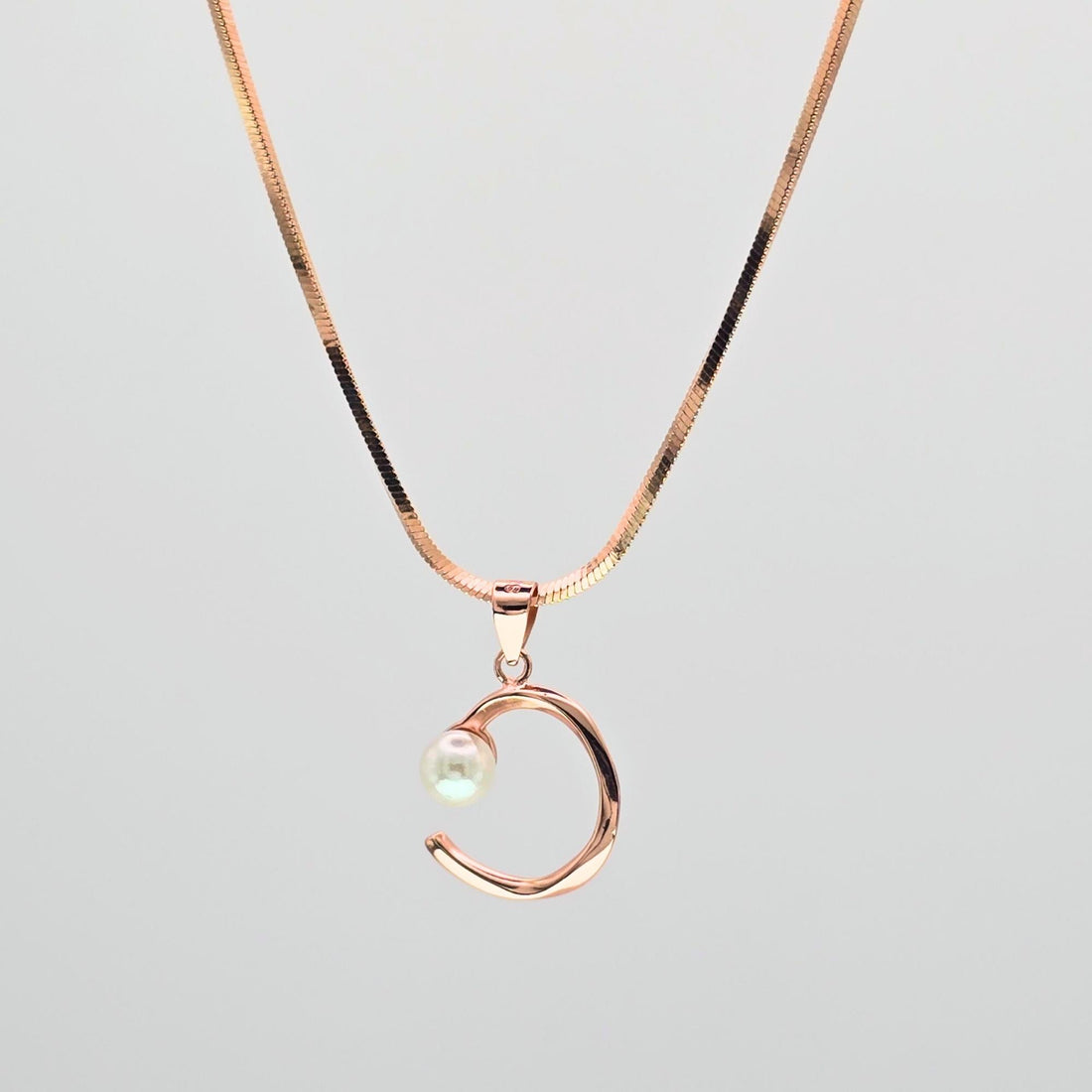 Rose gold necklace with a crescent moon pendant on a light gray background