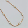 Rose gold necklace with pearls on a light gray background