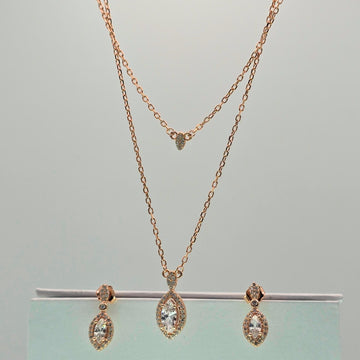 Rose gold necklace and earrings on a gray background