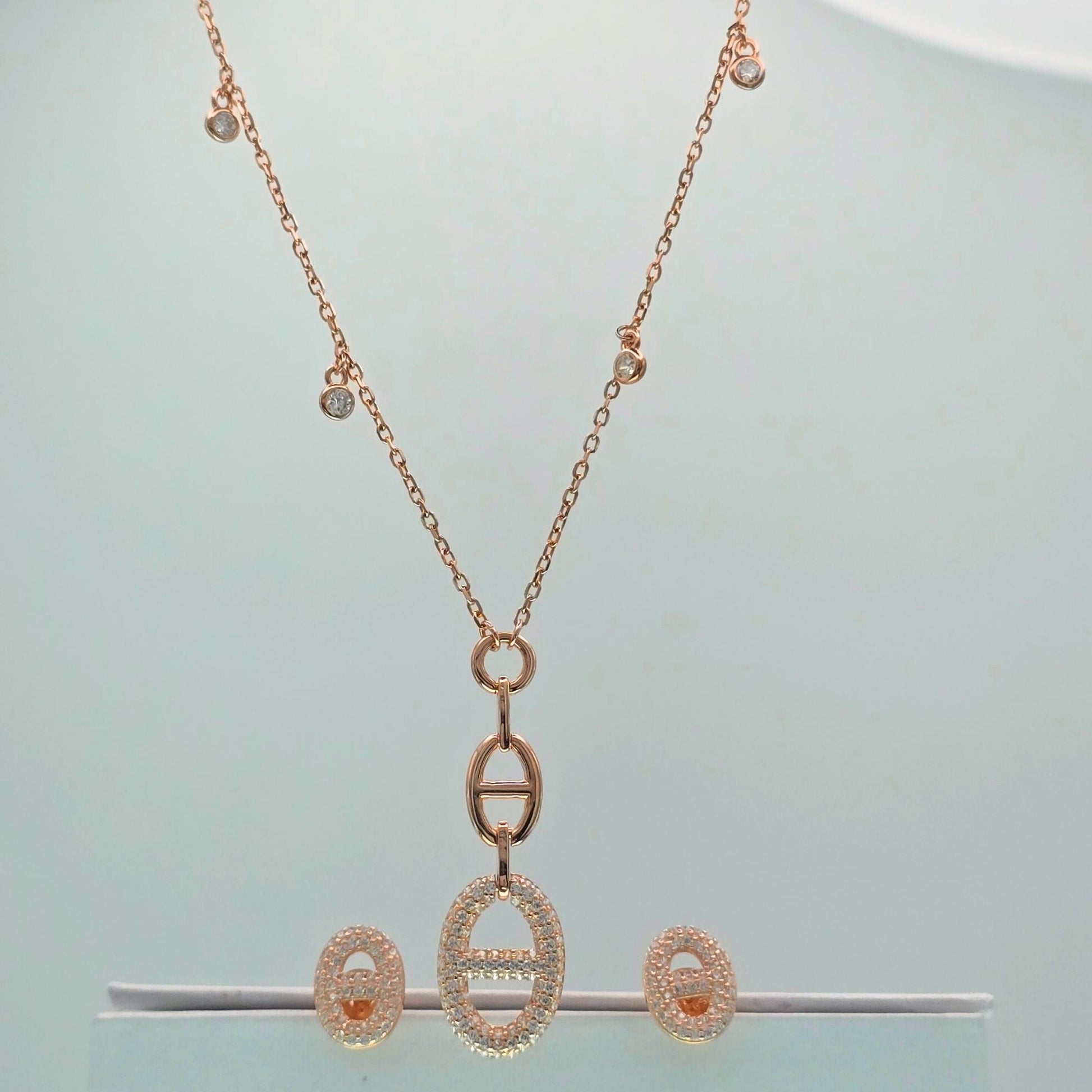 Rose gold necklace and earrings on a light blue background