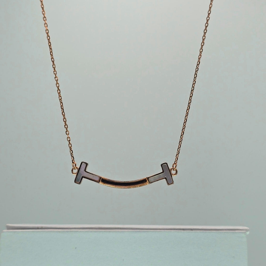 Gold necklace with a unique pendant on a light gray background