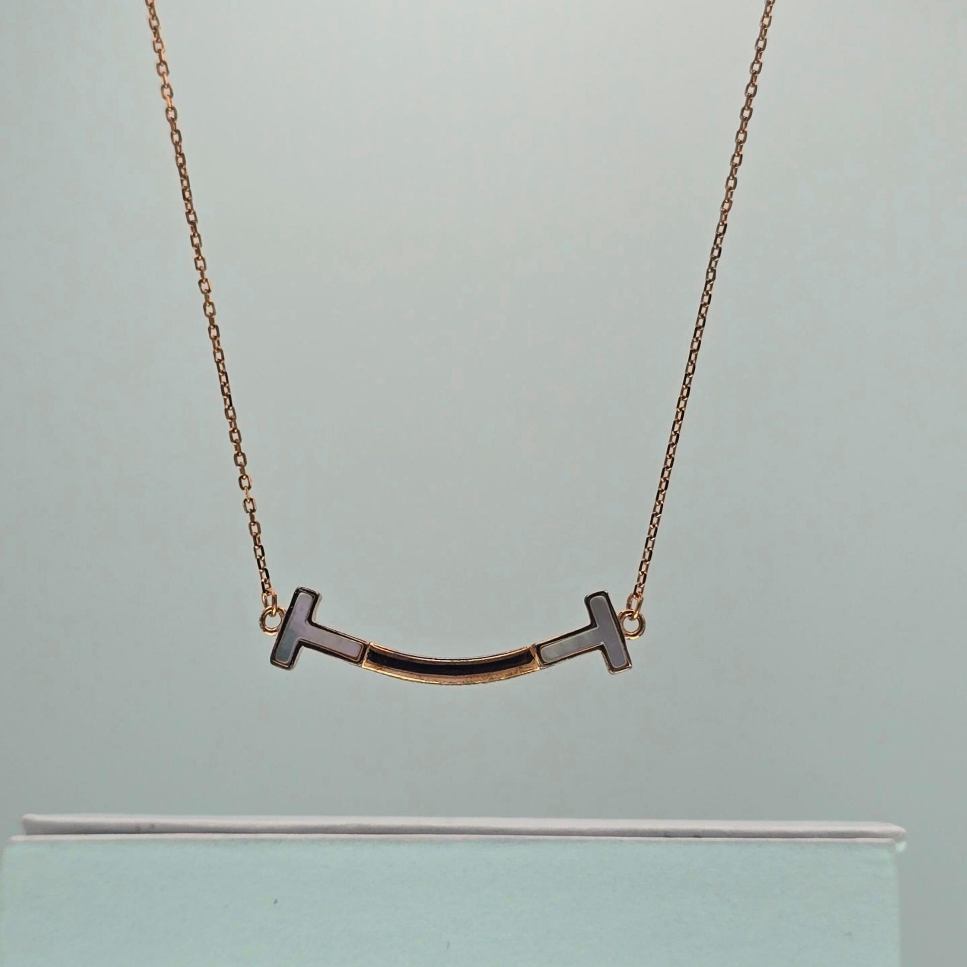 Gold necklace with a unique pendant on a light gray background