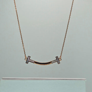 Gold necklace with a unique pendant on a light gray background