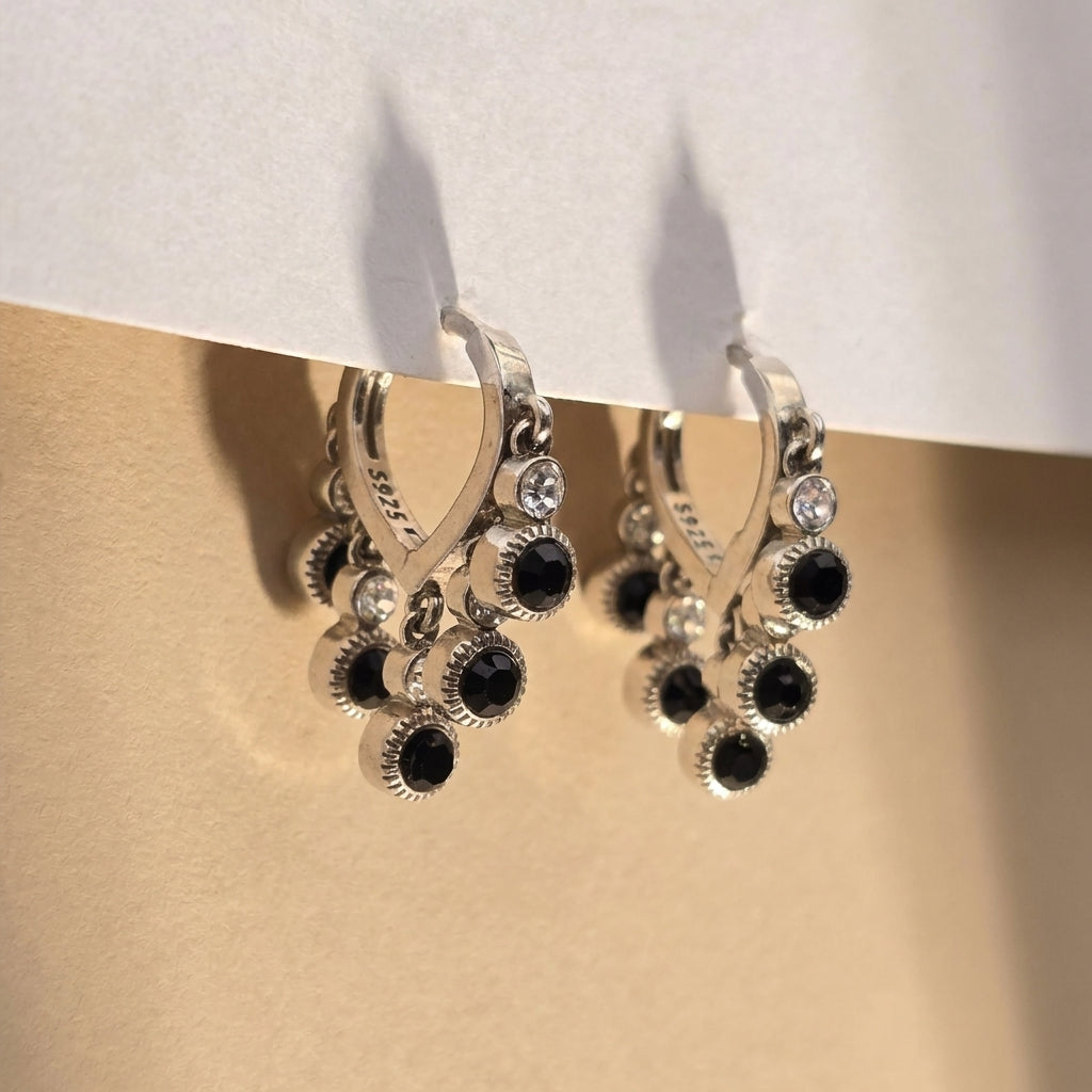 Silver ring with black gemstones on a beige surface