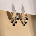 Silver ring with black gemstones on a beige surface