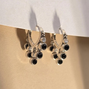 Silver ring with black gemstones on a beige surface