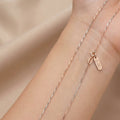Rose gold necklace on a person's wrist against a beige background
